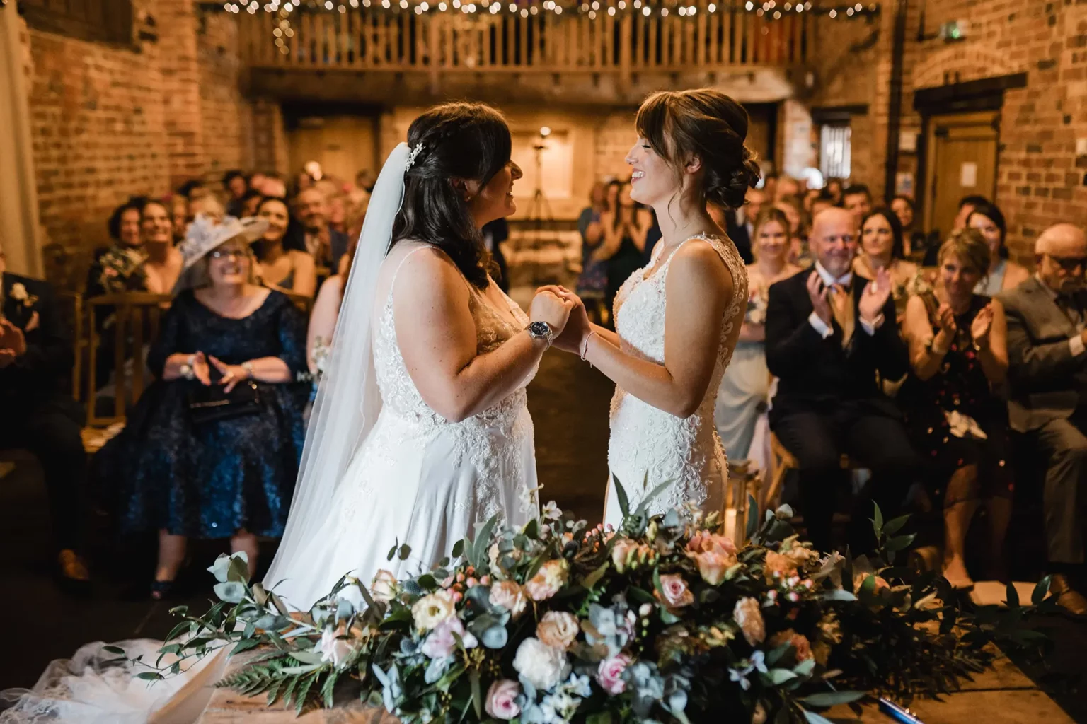 Curradine barns wedding ceremony brides holding hands in the granary barn