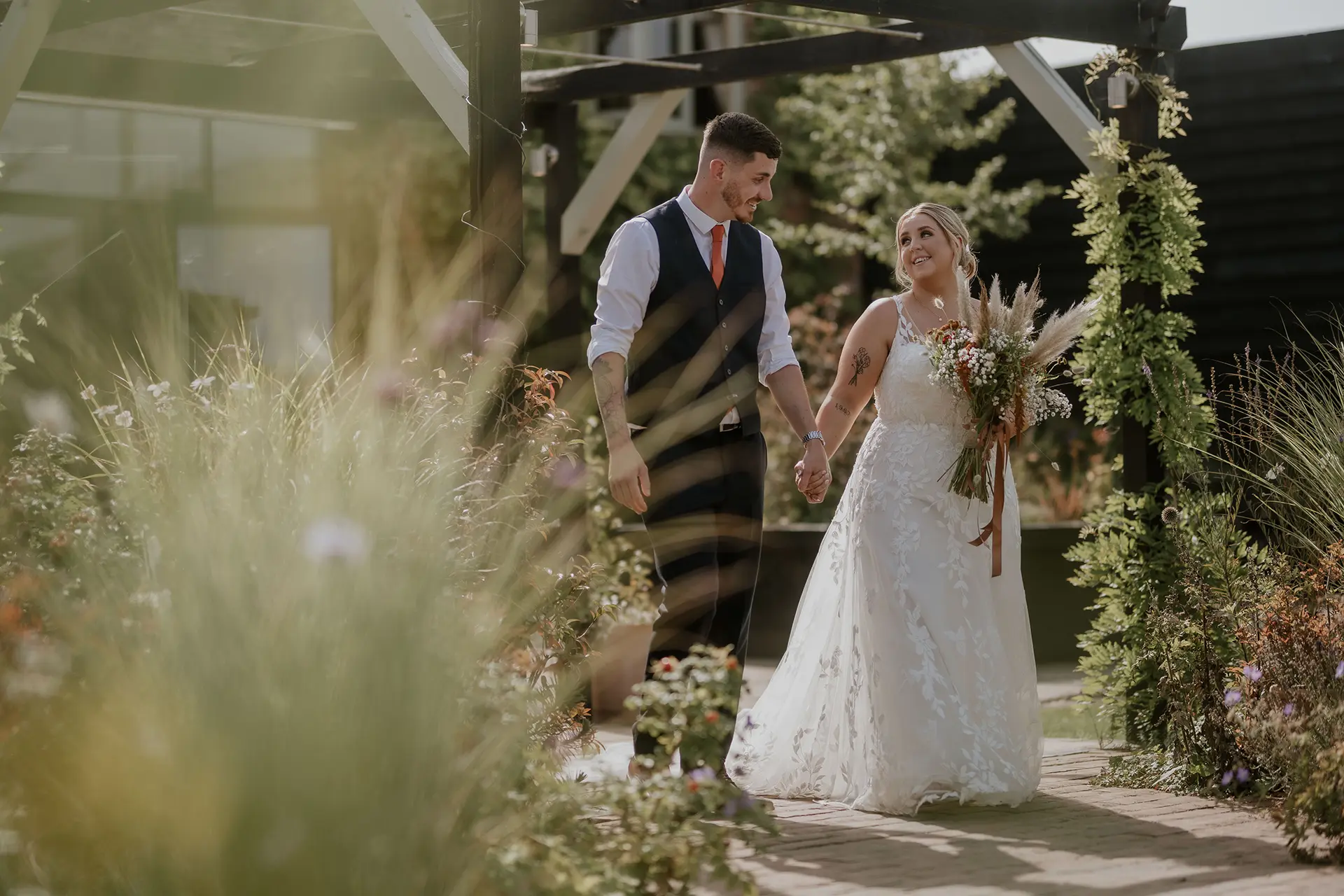 Curradine Barns couple holding hands in the entrance garden